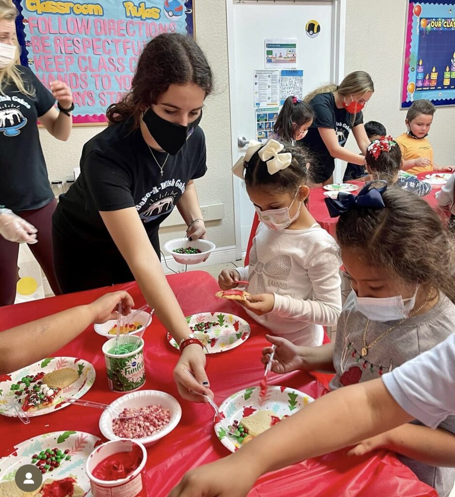 Volunteers helping children decorate cookies and treats during a holiday party