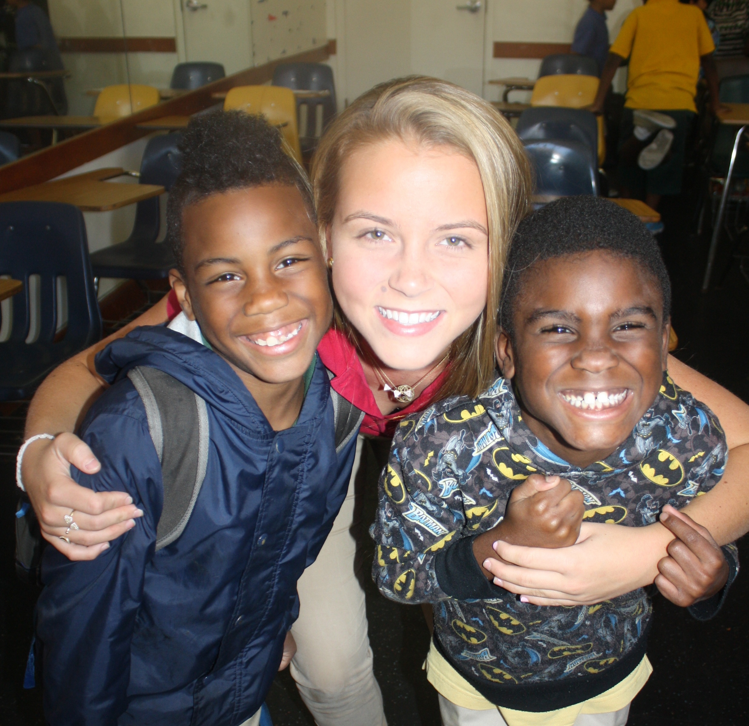 Volunteer with two smiling children in school cafeteria