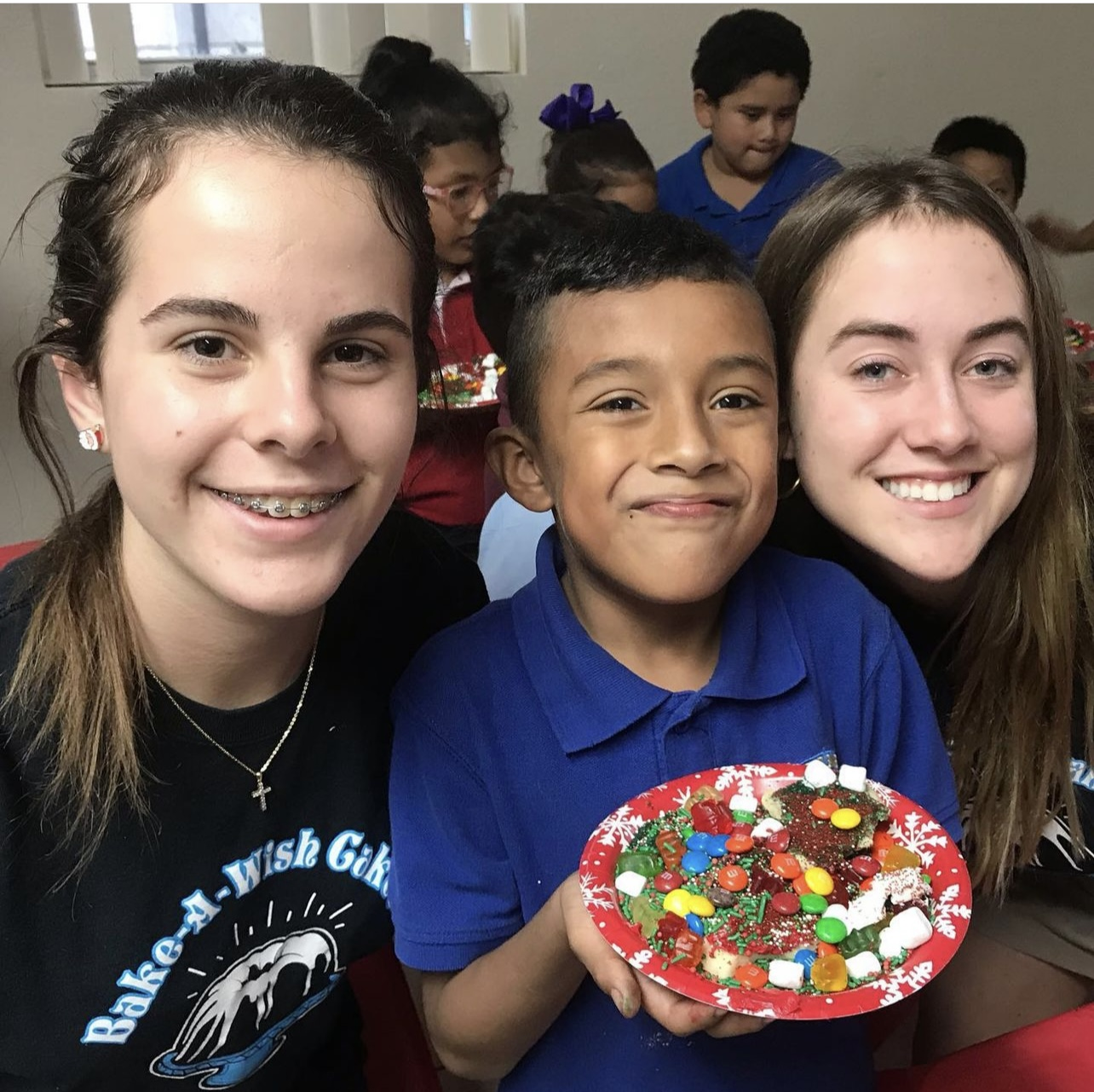 Bake-A-Wish volunteers with a happy child receiving a decorated cake